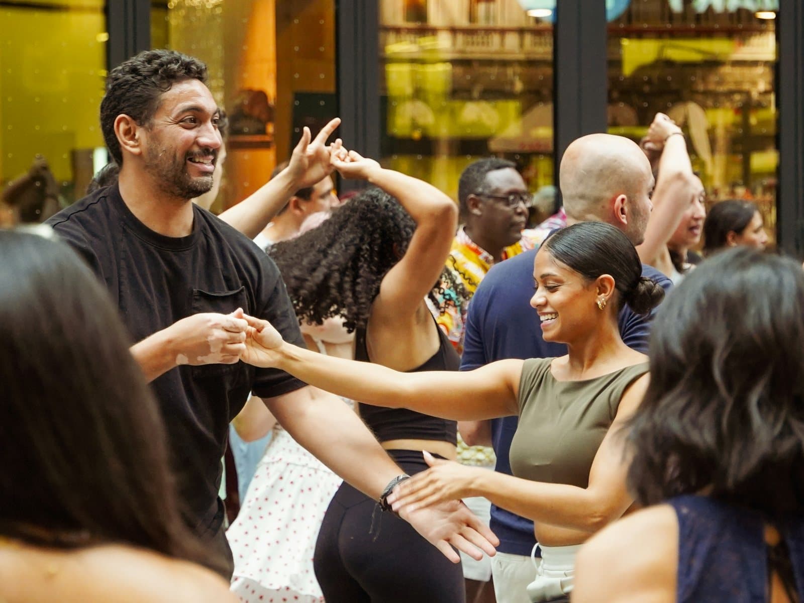 Smiling dancers pair up and spin during a lively group salsa night packed with people
