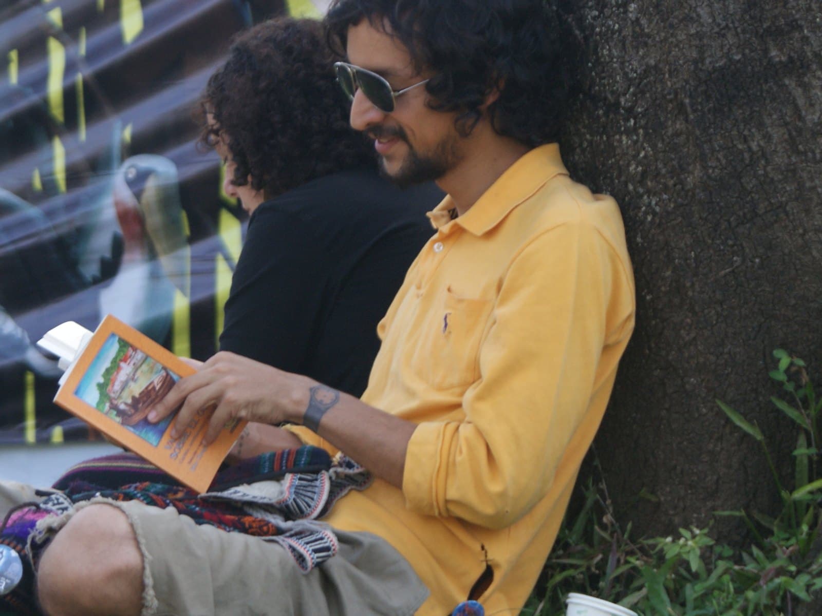 Relaxed reader with a book sitting on the grass under a tree at Medellín’s book fair