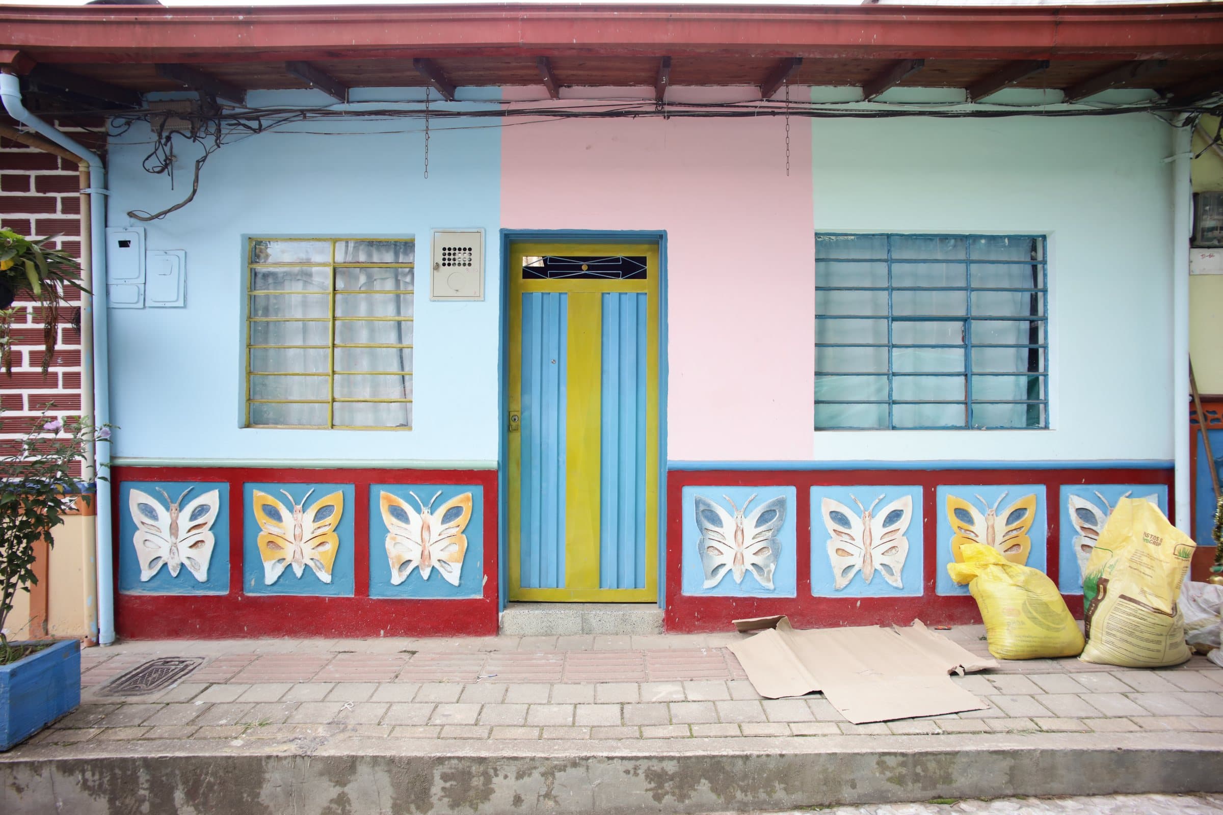Pastel pink and blue Guatapé house with a striped door and butterfly zócalo panels