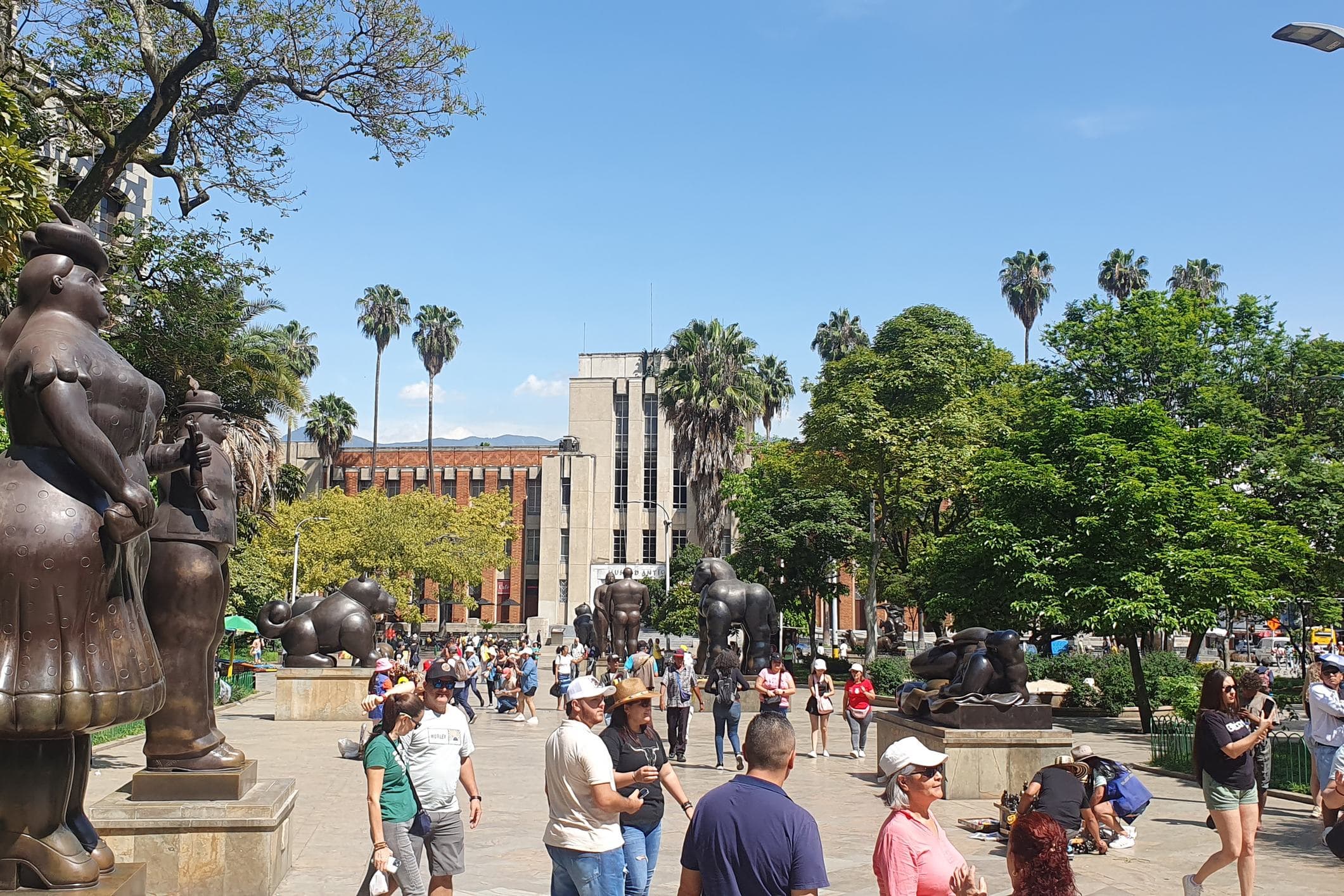 Relaxed crowds enjoy a sunny afternoon among Botero sculptures and palm trees