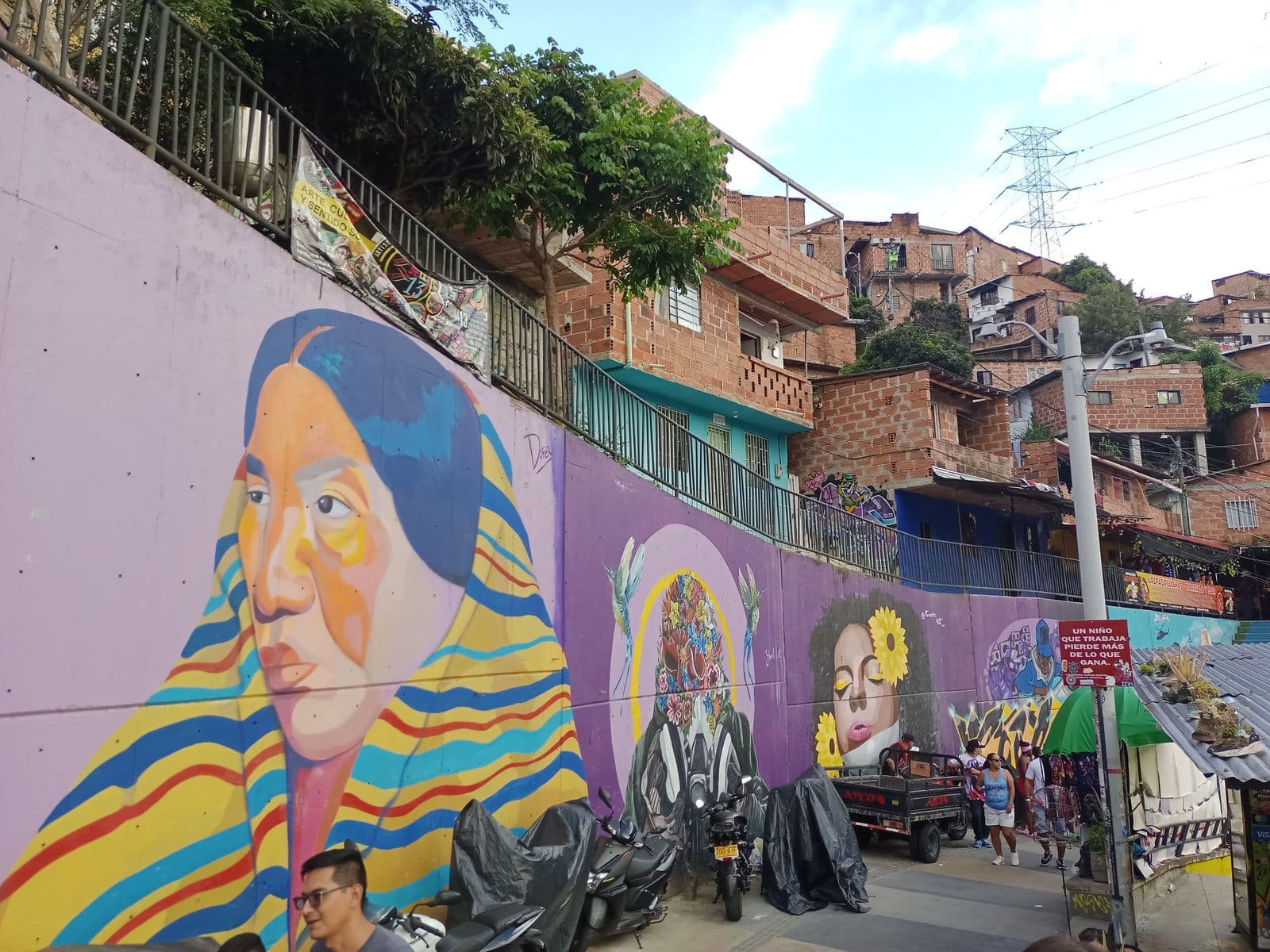 Murales vibrantes bordean una calle en ladera en un graffiti tour por Medellín