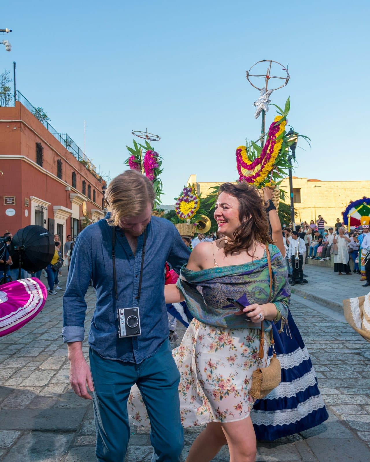Una pareja sonriente pasea por una calle empedrada y festiva adornada con flores de colores