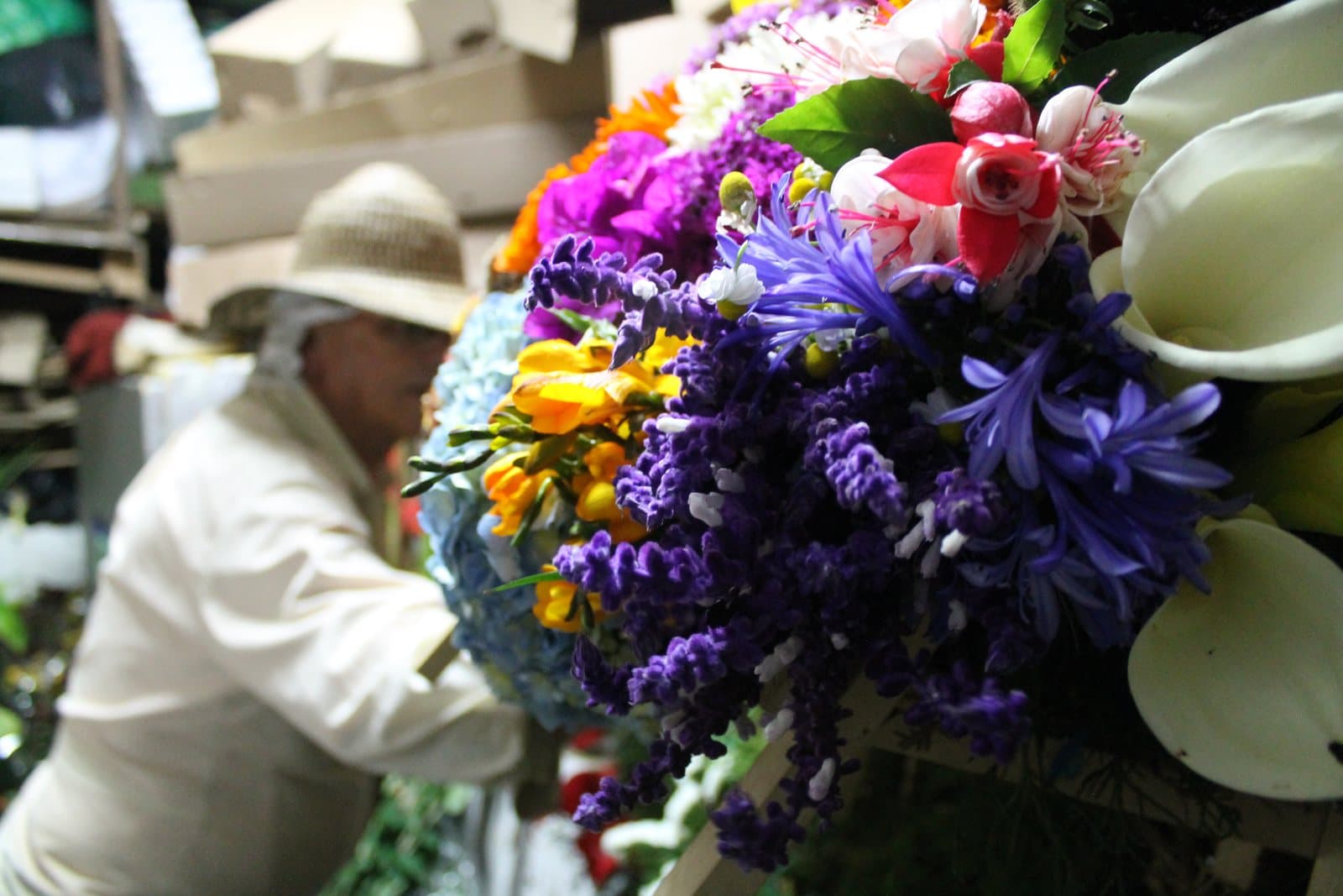 Silletero arranging a vivid purple, pink and white flower silleta in Santa Elena for the Feria de las Flores