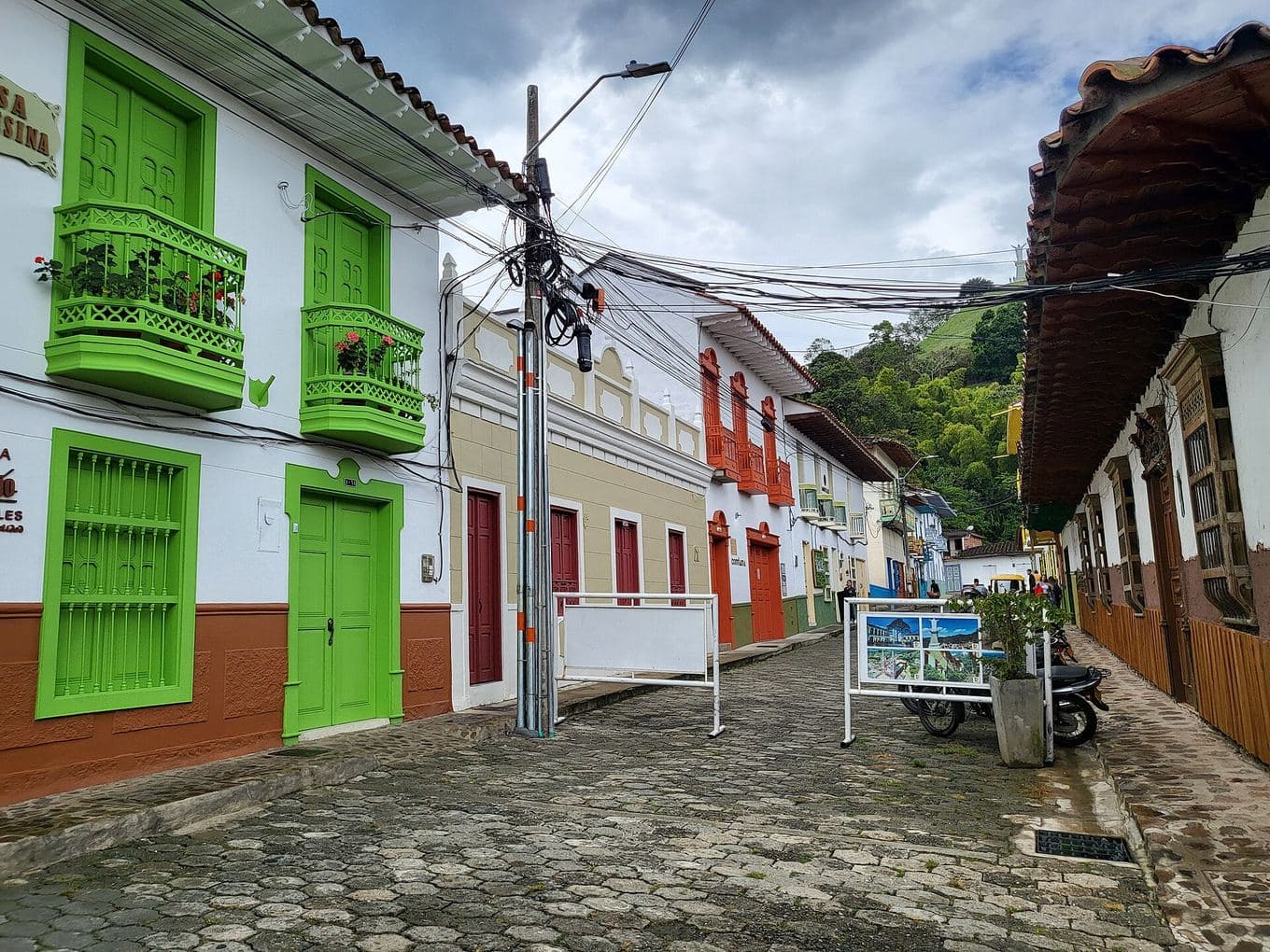 Balcones y puertas verde brillante en casas coloniales a lo largo de una calle empedrada en Jericó, Antioquia