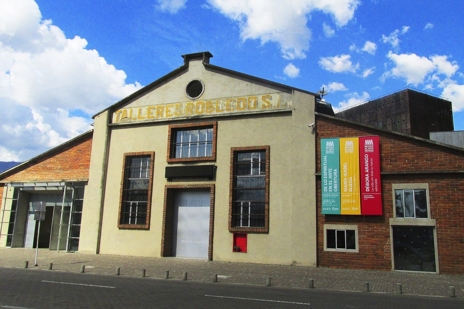 Restored Talleres Robledo brick facade of the Museo de Arte Moderno de Medellín under a vivid blue sky