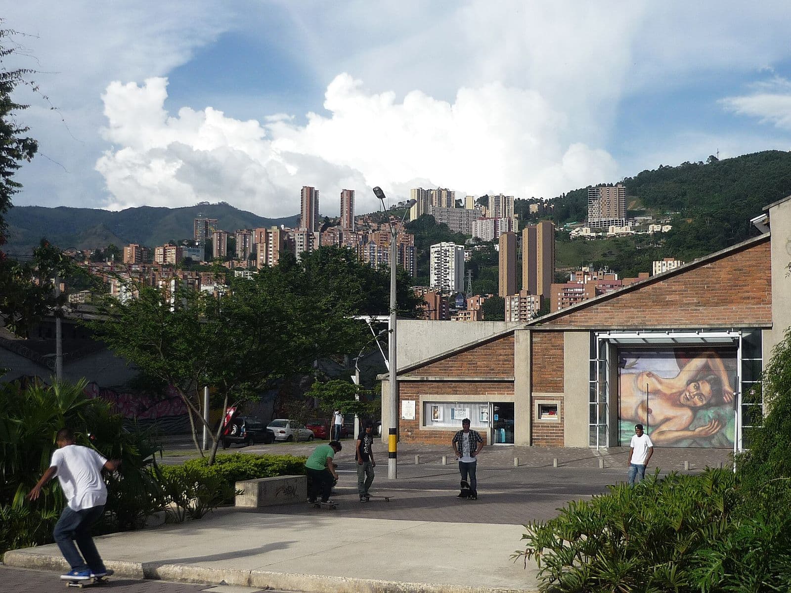 Plaza outside the MAMM in Ciudad del Río with a large mural and hillside towers behind