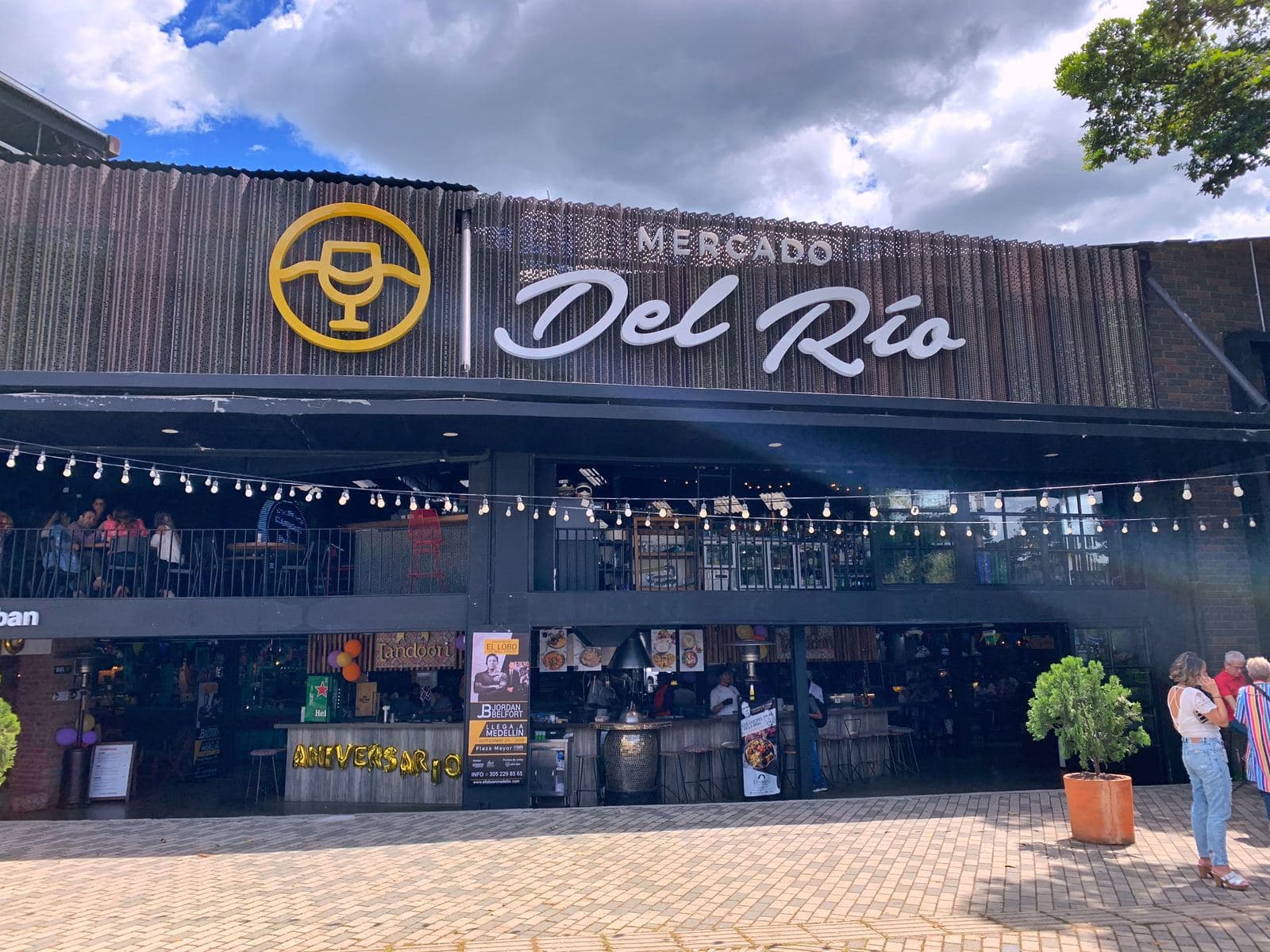 Mercado del Río's bold gold logo and entrance facade under a bright blue Medellín sky