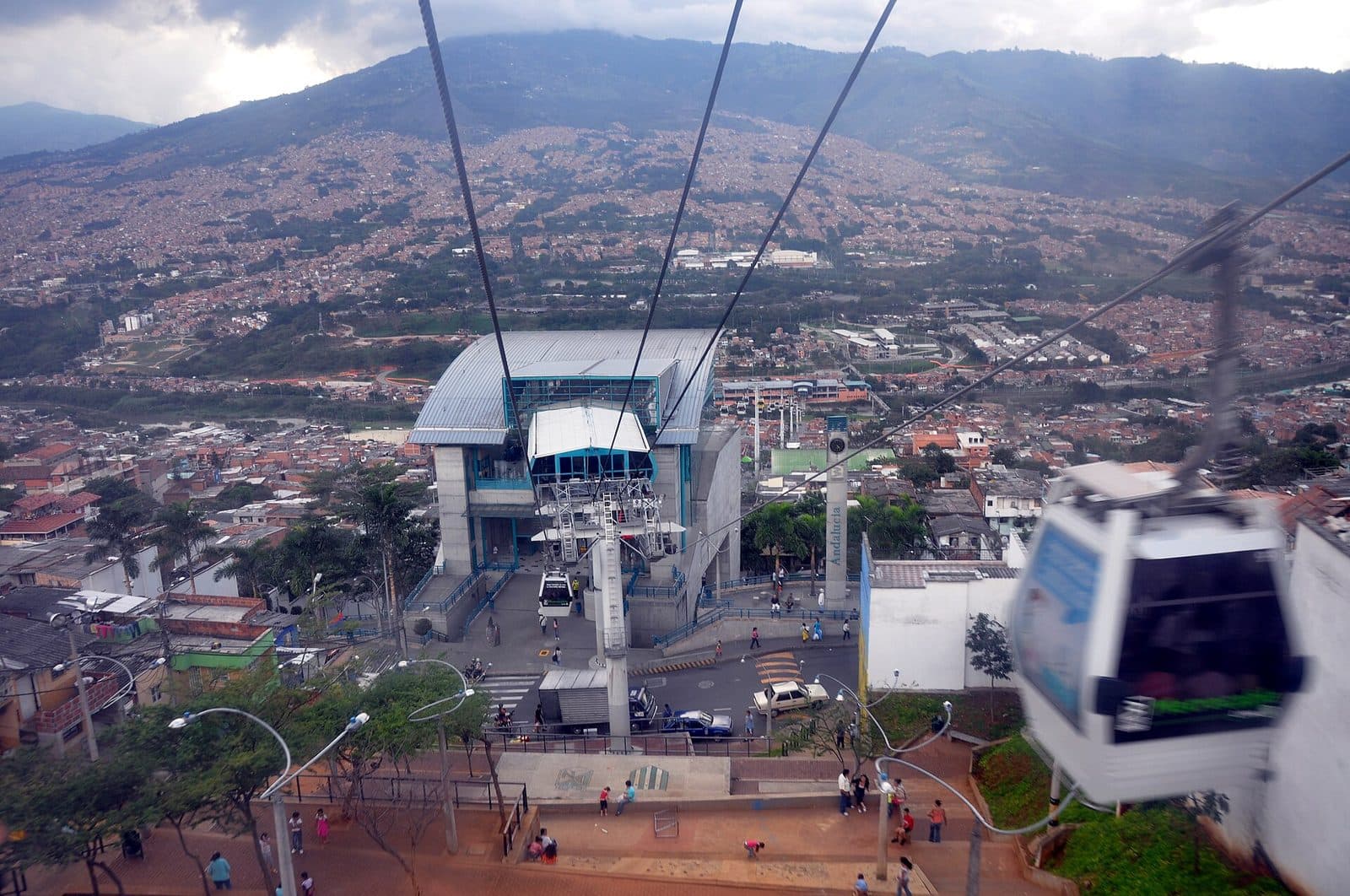 Metrocable cabin above a hillside station with Medellín's valley and mountains stretching behind
