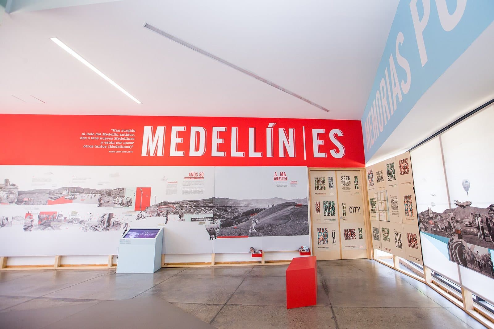 Bright exhibition hall with the red "Medellín es" timeline wall inside the Museo Casa de la Memoria