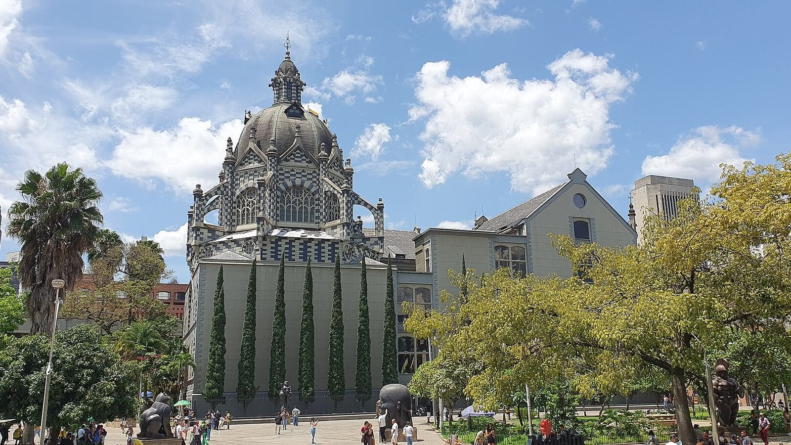 Palacio de la Cultura's black-and-white Gothic dome rising above Plaza Botero under a bright blue sky