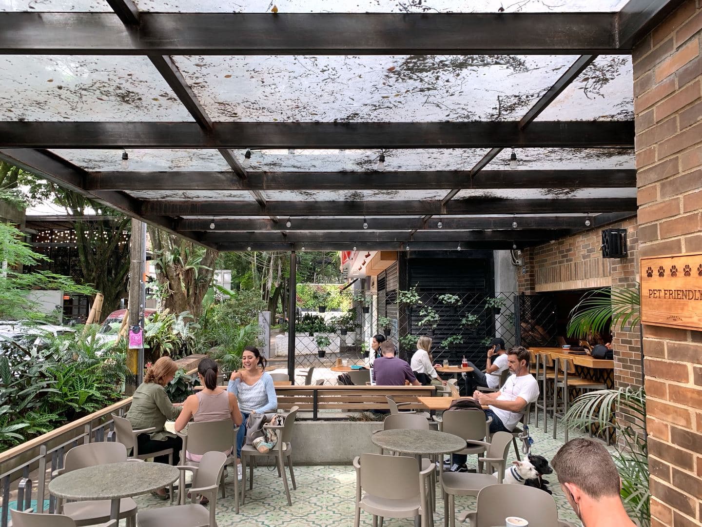 Leafy covered garden terrace with guests at tables in Pergamino Café, El Poblado, Medellín