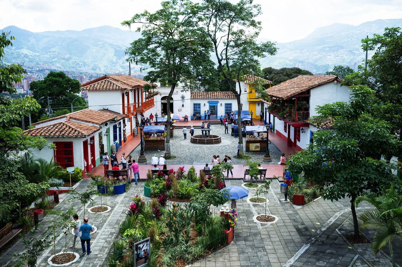 Casas coloniales blancas con balcones rojos alrededor de la florida plaza del Pueblito Paisa, en la cima del Cerro Nutibara