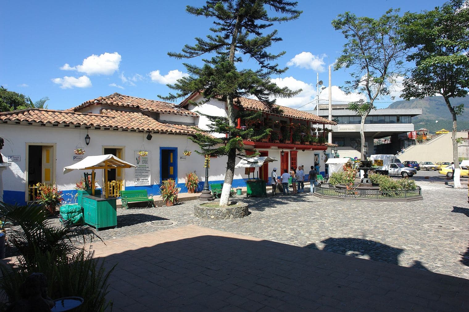 Plaza empedrada y soleada del Pueblito Paisa con casas de techo de teja y pinos en el Cerro Nutibara