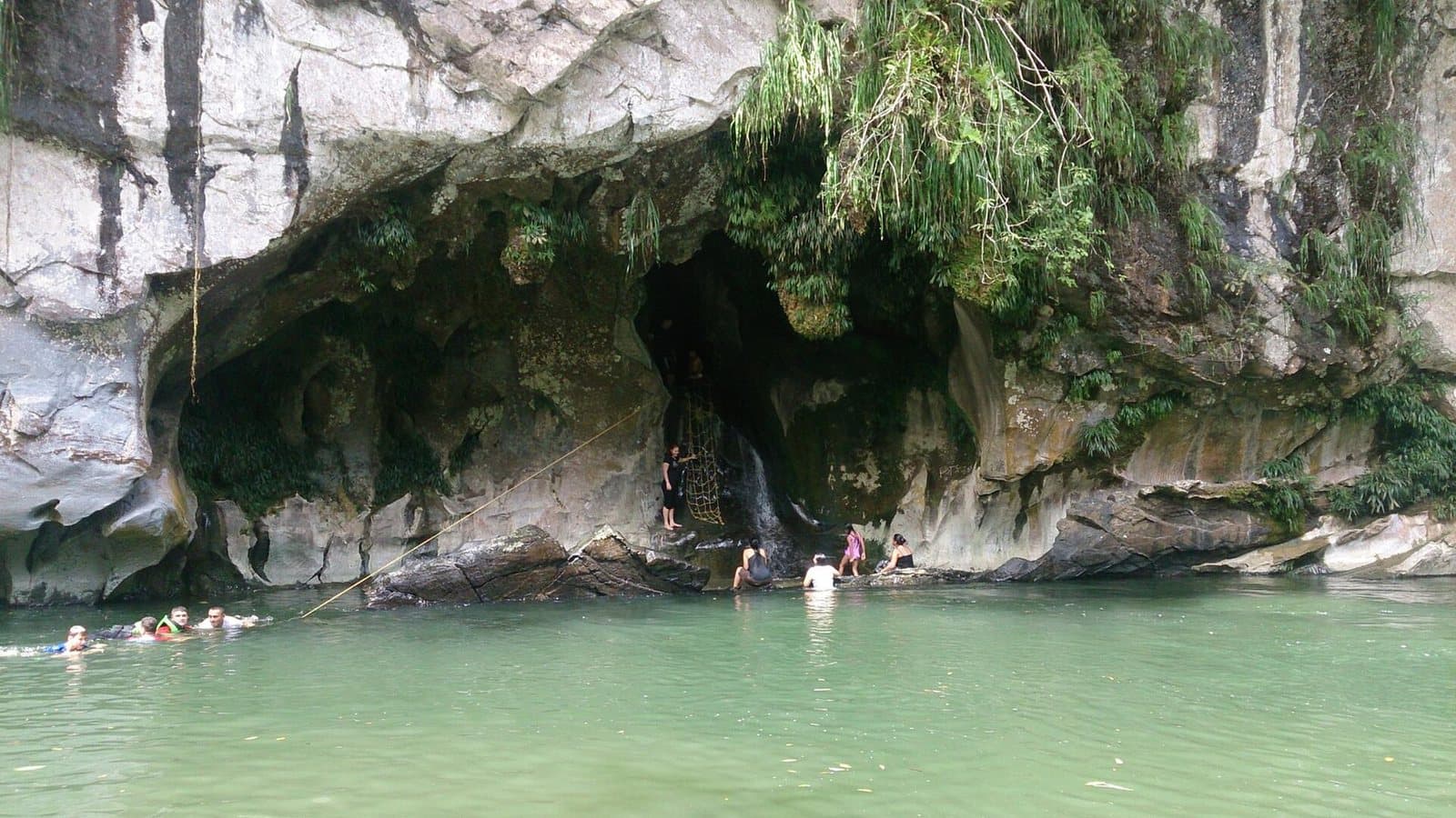 Swimmers floating in jade water beneath the white marble cave walls of the Río Claro canyon