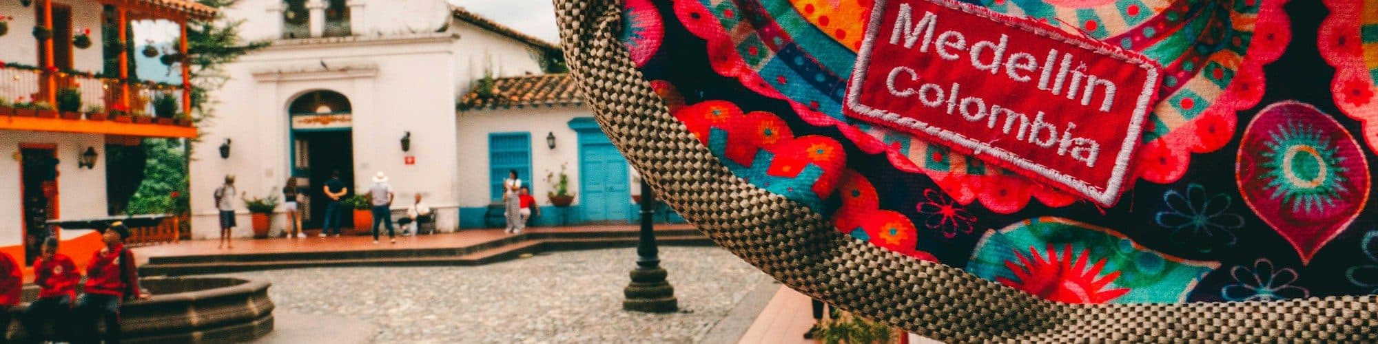 A colorful woven Medellín bag in front of a bright colonial plaza